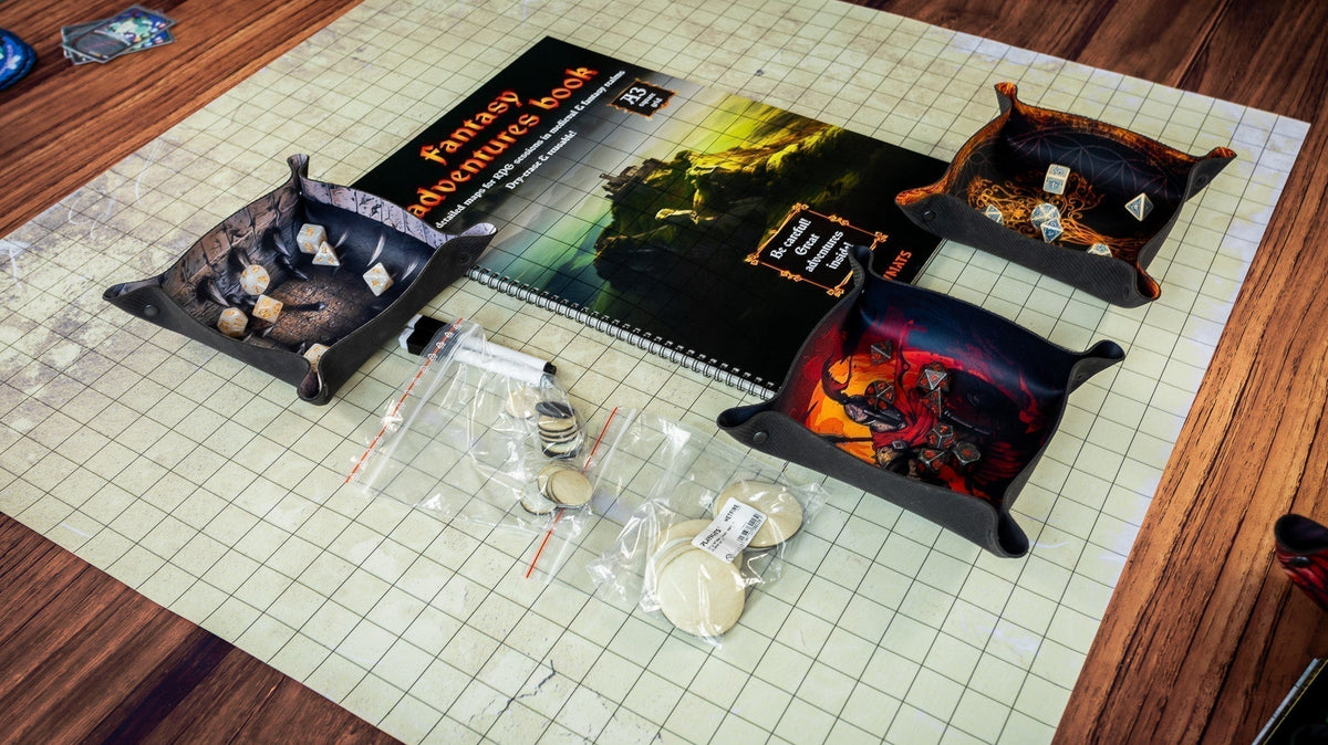 RPG accessories arranged on a grid mat, including a fantasy map book, dice trays, dice and tokens.