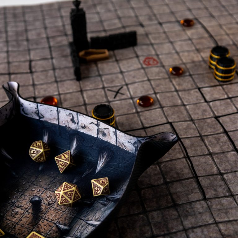 RPG mat with a square grid, terrain pieces and markers, with gold-coloured dice in a fantasy-themed dice tray.