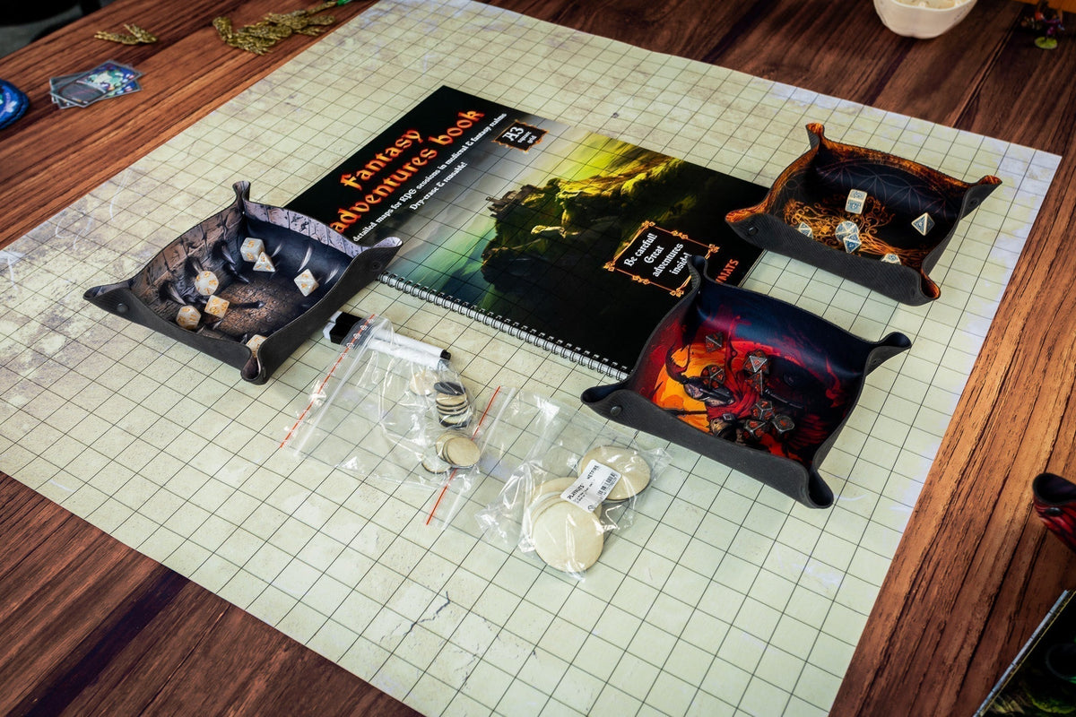 RPG accessories arranged on a grid mat, including a fantasy map book, dice trays, dice and tokens.